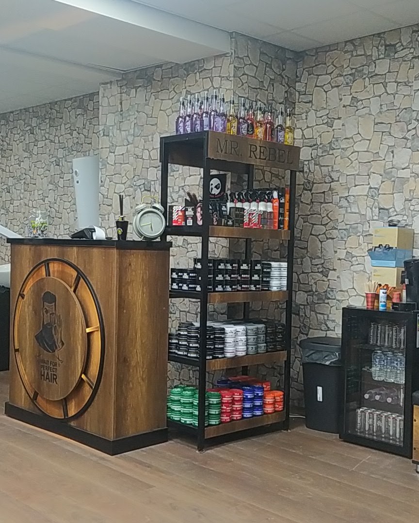 De houten balie met een rond barbiersembleem en een wandkast vol haarproducten, voor de stenen muur