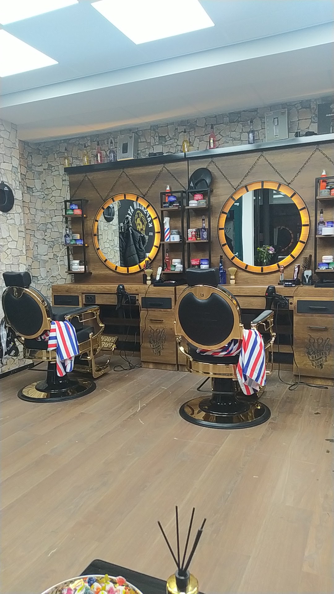 Twee kappersstoelen met gestreepte kapmantels voor twee ronde spiegels met gouden rand
